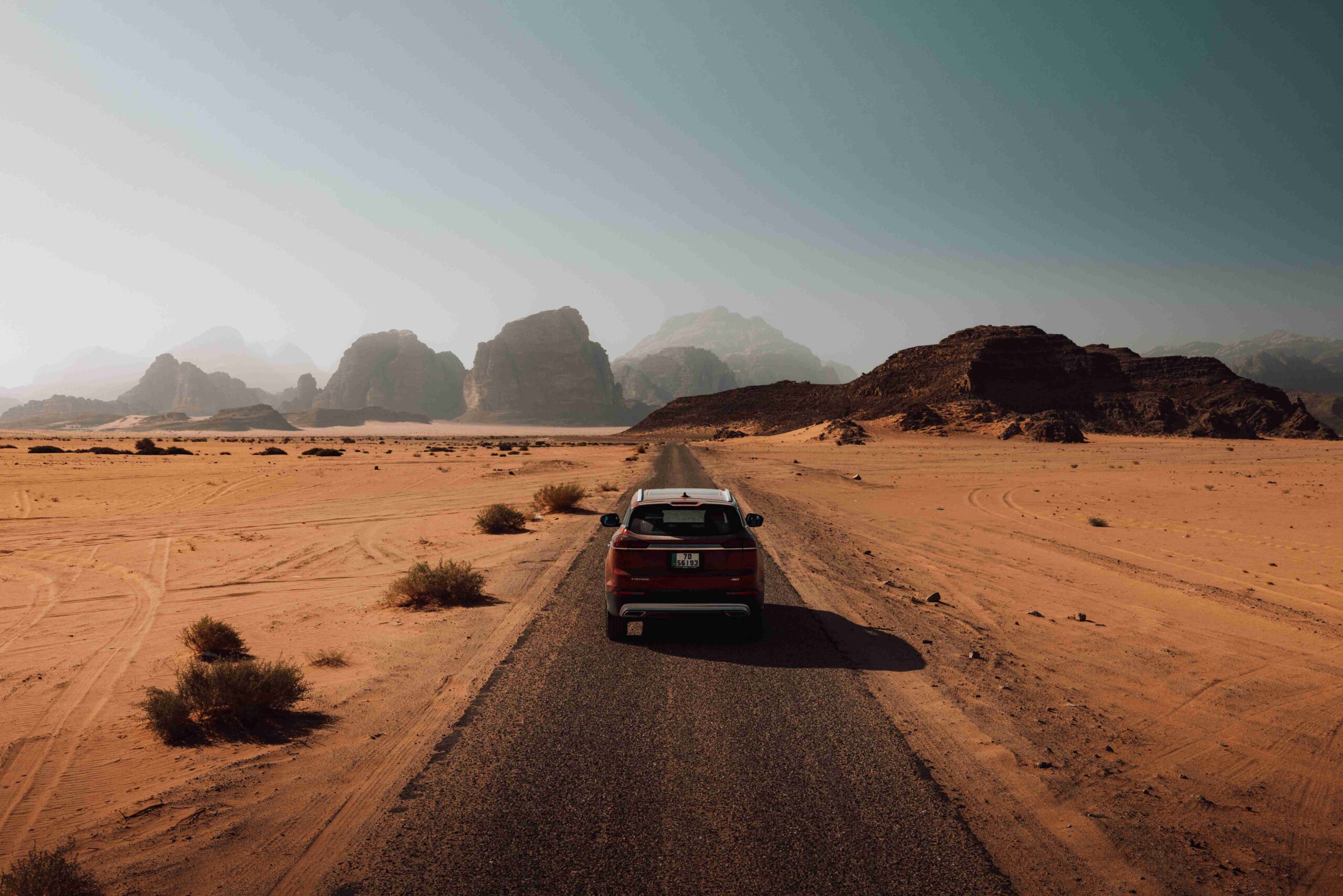 voiture sur une route au milieu du désert lors d'un road trip en Jordanie